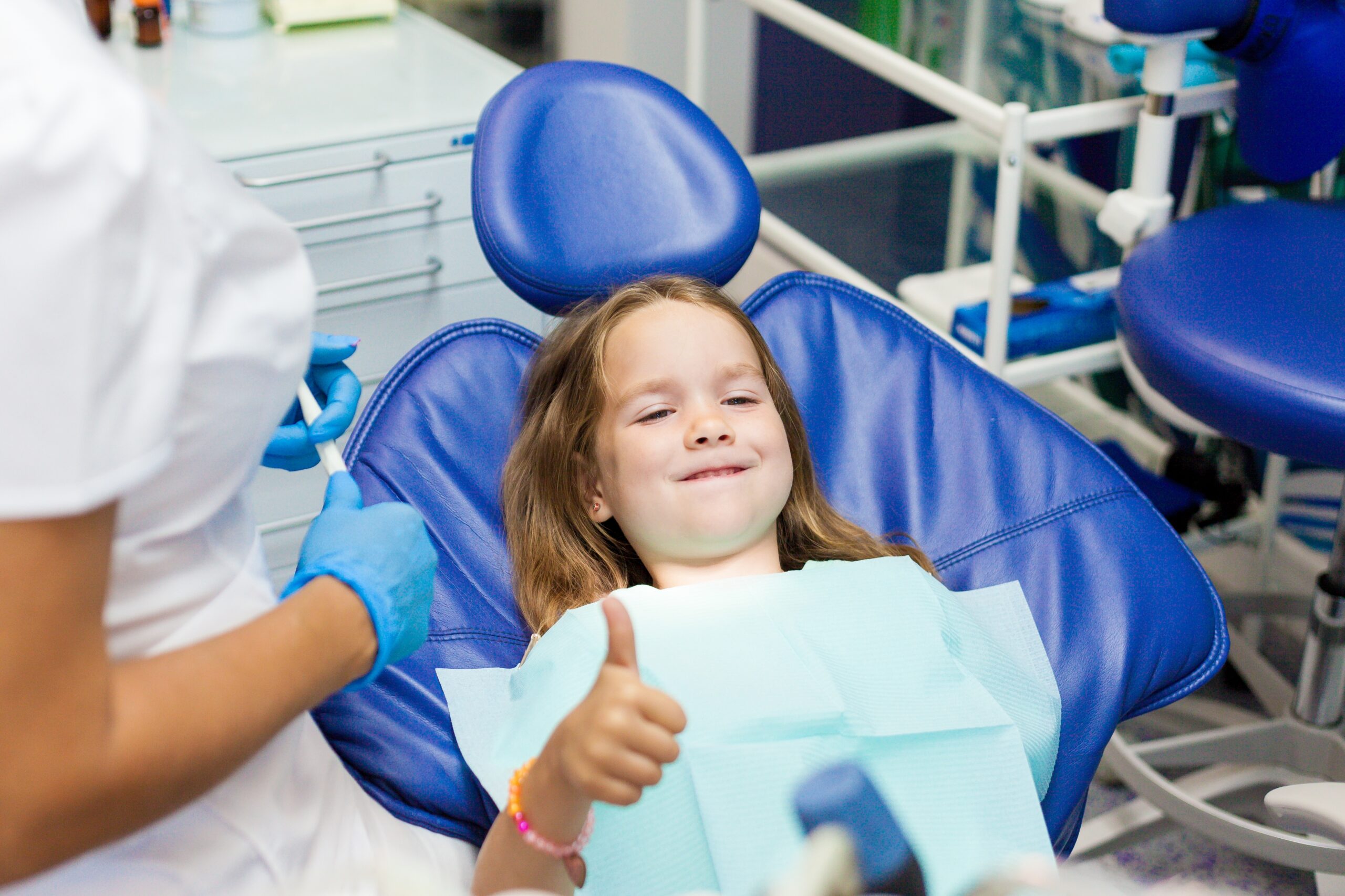 Kid giving thumbs up sitting while lying in the dental chair for a dental checkup