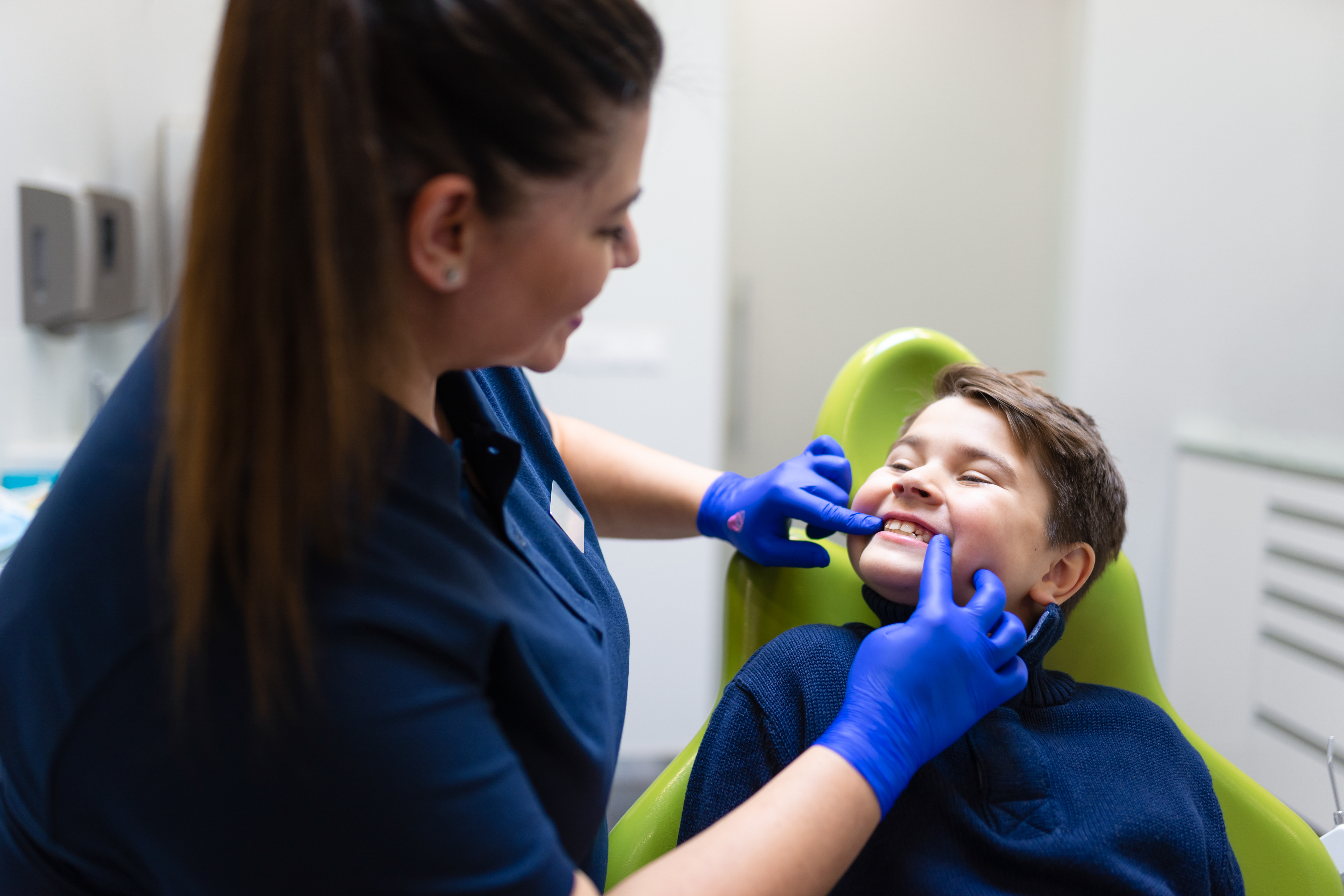 Dentist visually assesses the condition of the teenager's teeth. Boy at the dentist