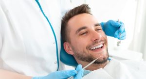 a man is smiling while a dentist examines on his teeth for root canal the dentist is wearing blue gloves and holding