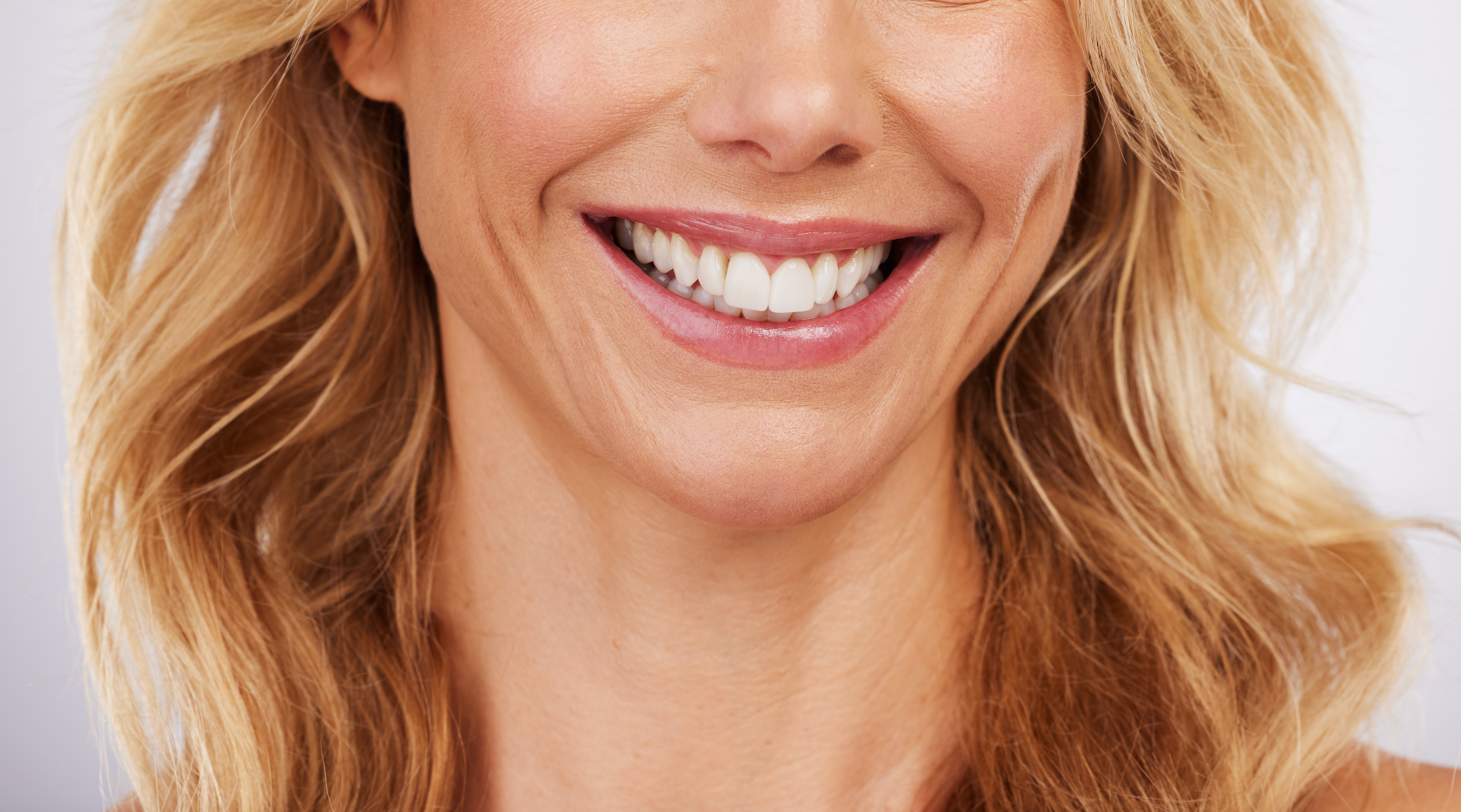 Closeup, smile and woman mouth in studio for dental, hygiene or teeth whitening on grey background