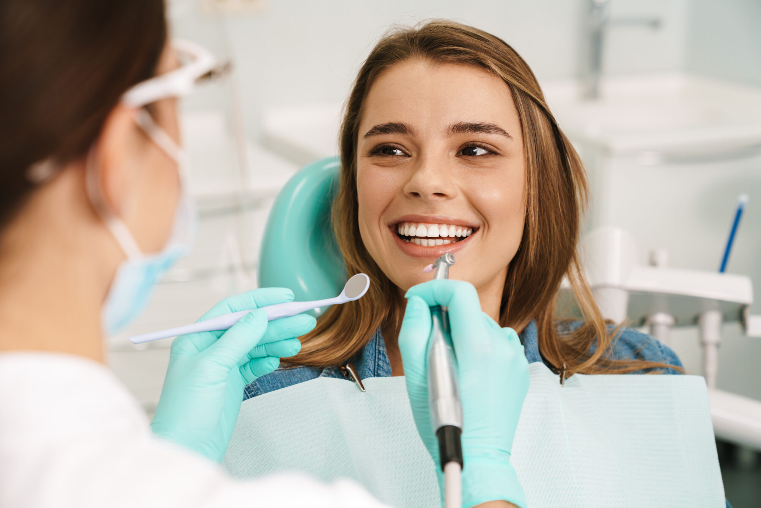 Australia smiling woman sitting in medical chair while dentist checks her teeth at dental clinic