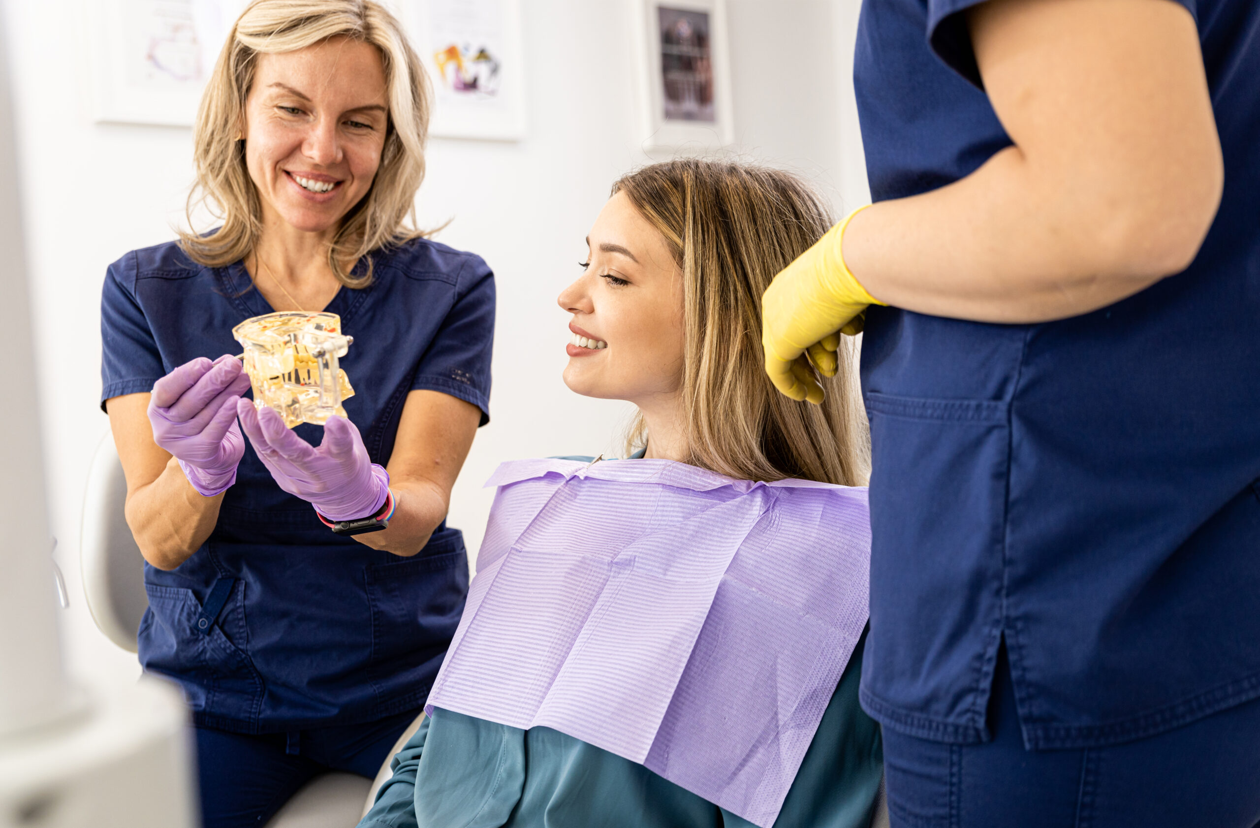 Female dentist talking with patient showing teeth implant in dental clinic