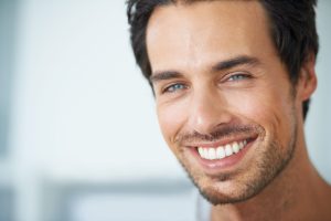 Closeup portrait of a handsome young man smiling with dental implants